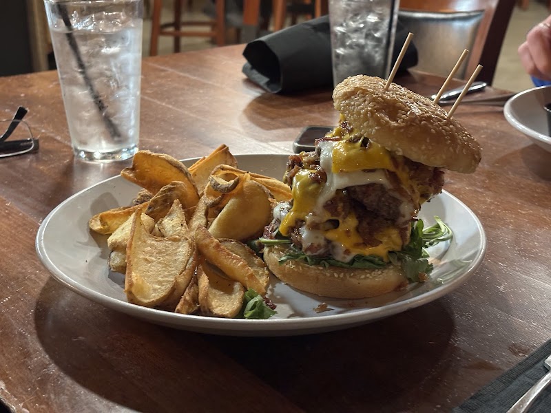 Plate with a loaded cheeseburger and thick potato wedges on a wooden table at Badlands National Park restaurant scene.