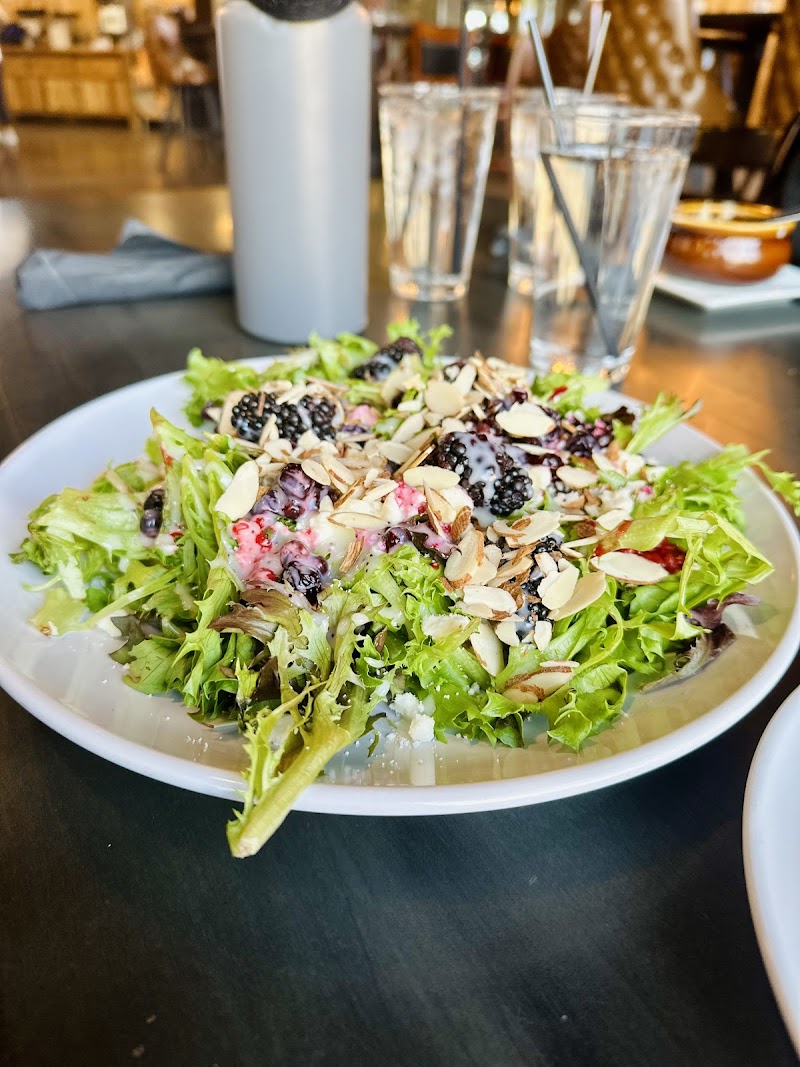 Fresh green salad piled high with blackberries, almond slices, and feta, served in a casual restaurant near Badlands National Park.