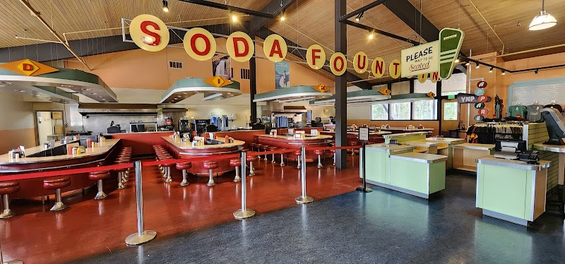 Retro general store with a long red counter, red stools, soda fountain signage, and green checkout desks in Yellowstone.