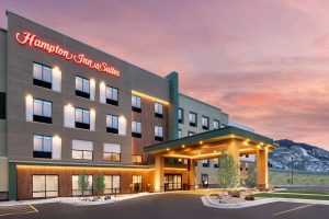 Lodging exterior in Cody near Yellowstone National Park, a modern hotel with illuminated entry and warm dusk lighting.