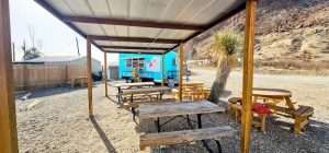 Covered outdoor dining area with wooden picnic tables at a desert roadside grill in Big Bend National Park.