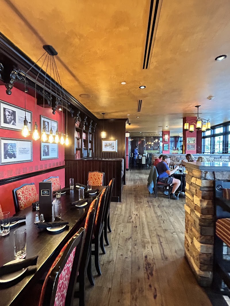 Inside a cozy restaurant in Acadia National Park with a long dark wooden table, red walls, framed photos, and hanging bulbs.
