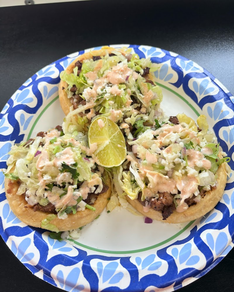 Three tacos topped with lettuce, cheese and crema on a blue patterned plate with a lime wedge in Yellowstone National Park.