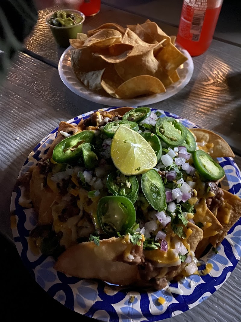 Plate of loaded nachos with jalapeños, onions, cilantro and a lime wedge, at a table in Yellowstone National Park.