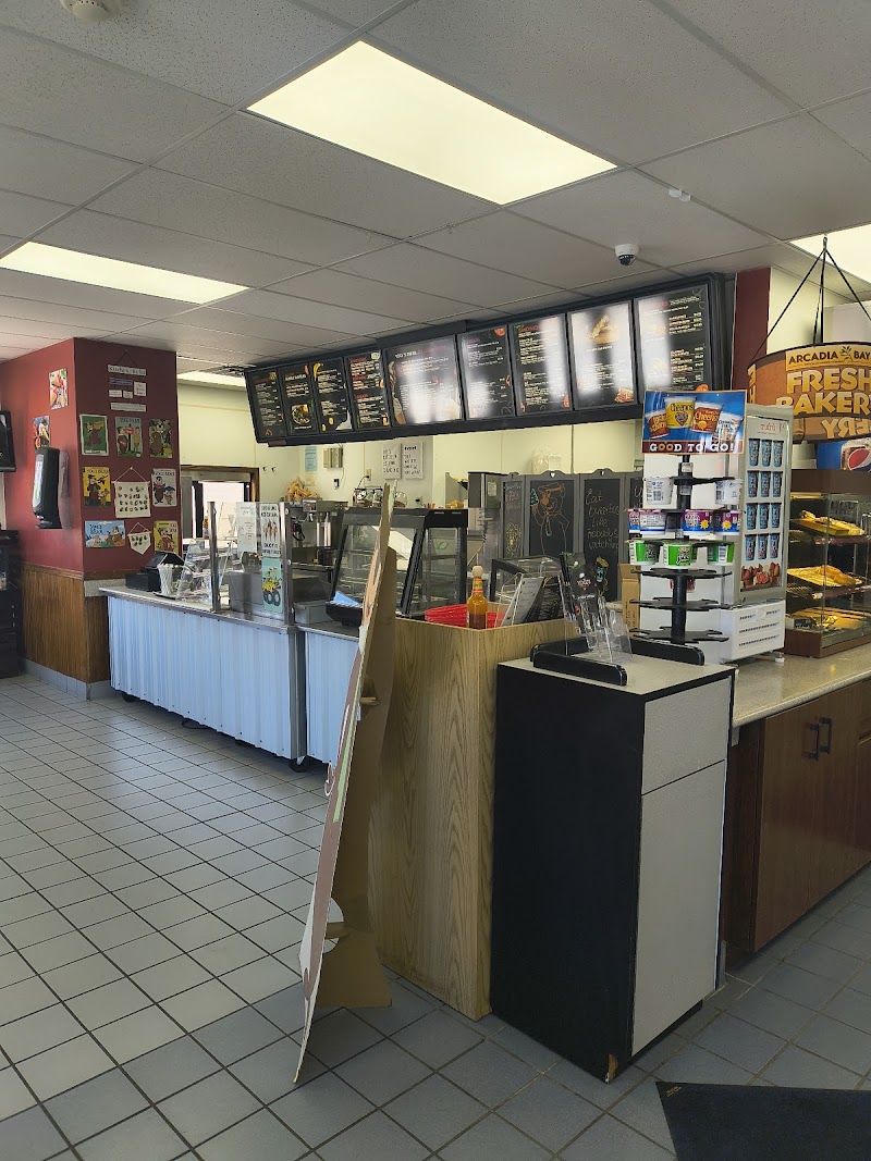 Inside a casual eatery in Yellowstone National Park, a light-blue counter with glass food displays and a menu board.