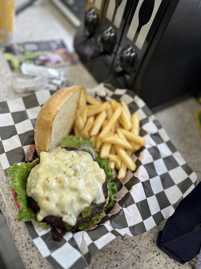 Burger with creamy cheese sauce, lettuce and onions, plus golden fries on checkered paper at Yellowstone National Park.
