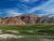Interior landscape at Badlands National Park with layered red and gray badlands, rolling flats and blue sky.