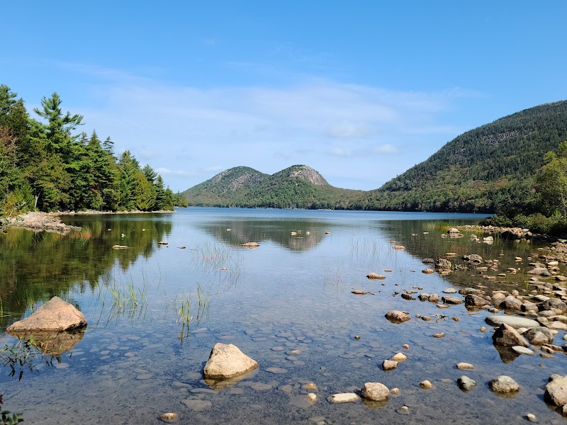 Jordan Pond in Acadia National Park reflects forested shores with the Bubbles rising beyond.