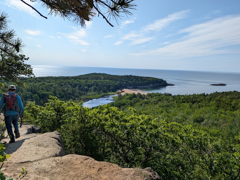 Hiker at a rocky Cadillac Mountain overlook in Acadia National Park gazes over Frenchman Bay.