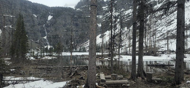 Lincoln Lake Campground along Lincoln Lake in Glacier National Park shows snow-dusted pines and a tranquil lakeside clearing.