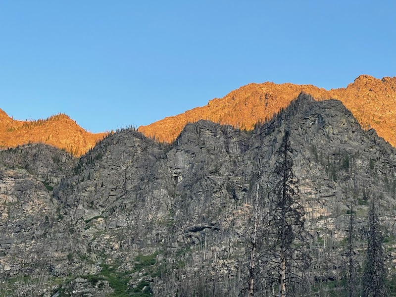 Sunlit granite peaks over a campground near Lincoln Lake in Glacier National Park.