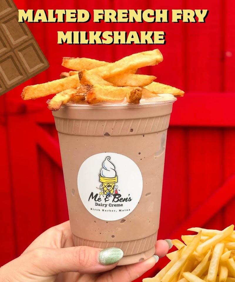 Malted French Fry Milkshake served in a cup with fries on top, photographed near a red wooden fence at Acadia National Park.