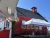 Red wooden dairy shop storefront with a white canopy and seating under blue sky in Acadia National Park.