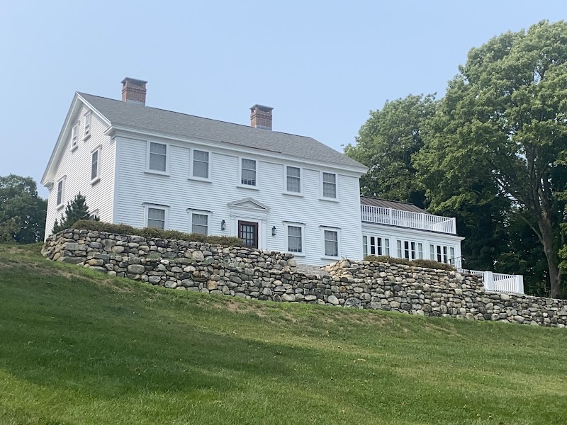 Castine house on a grassy hill with a stone terrace in Acadia National Park, Maine.