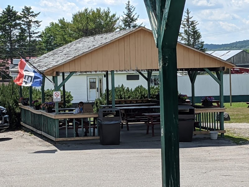 Drive-in restaurant pavilion at Acadia National Park with a shaded deck, picnic tables, and a small white building in the background.