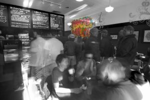 Busy cafe interior at Arches National Park with chalkboard menus and a crowd of blurred patrons.