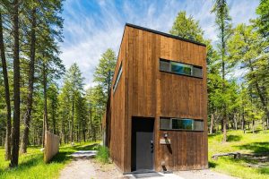Wood-clad lodging cabin nestled among pines at Glacier National Park, showcasing modern design.