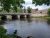 Ellsworth town bridge over a calm river near Acadia National Park, with brick buildings and green trees.