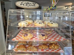 Pastry display case inside J.M. Gerrish Cafe at Acadia National Park, showing assorted donuts and pastries.