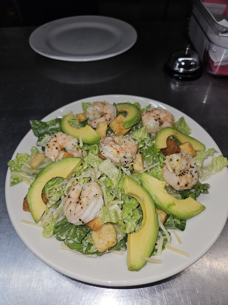 Shrimp and avocado salad served at a cafe in Acadia National Park, with lettuce, croutons and shredded cheese on a white plate.