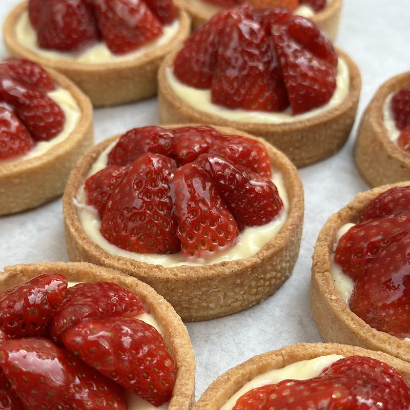 Mini tart shells with creamy filling and bright strawberries arranged on parchment in Acadia National Park.