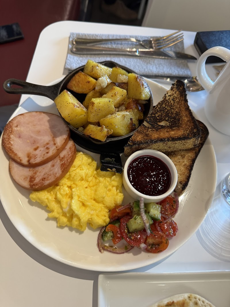 Breakfast plate with scrambled eggs, sliced ham, crispy home fries, toasted bread, berry jam, and a tomato-onion cucumber salad, Acadia National Park.