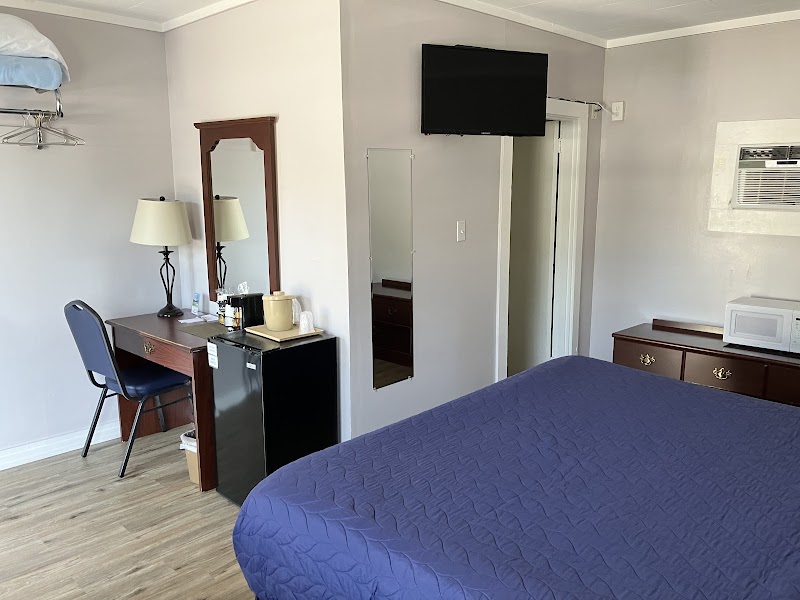 Cozy Acadia National Park motel room with a blue quilt bed, desk and chair, mini fridge, dresser, wall TV, and microwave.