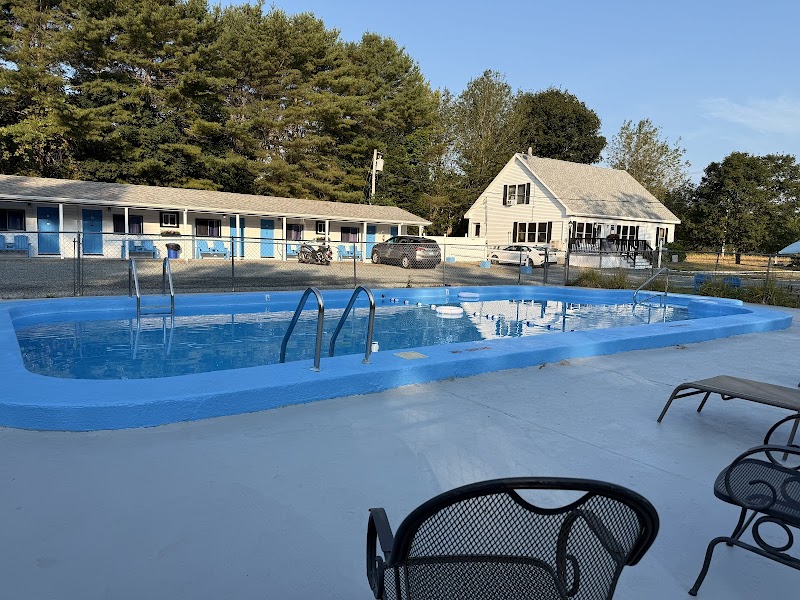 Blue outdoor pool with metal ladders, surrounding metal chairs, and a row of blue-and-white motel buildings at Acadia National Park.
