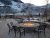 Gardiner fire pit plaza with cast-iron seating in a snowy Yellowstone setting overlooking the surrounding mountains.