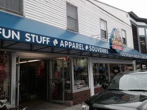 Acadia National Park storefront with a blue awning reading Fun Stuff Apparel Souvenirs, glass windows, and a parked SUV.