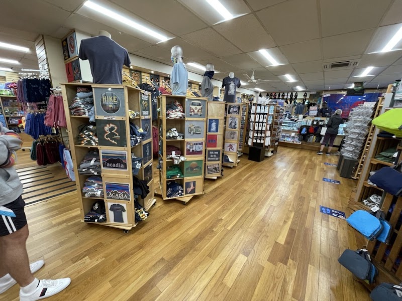 Inside a gift shop at Acadia National Park, wooden shelves display shirts and hats as mannequins wear tees.