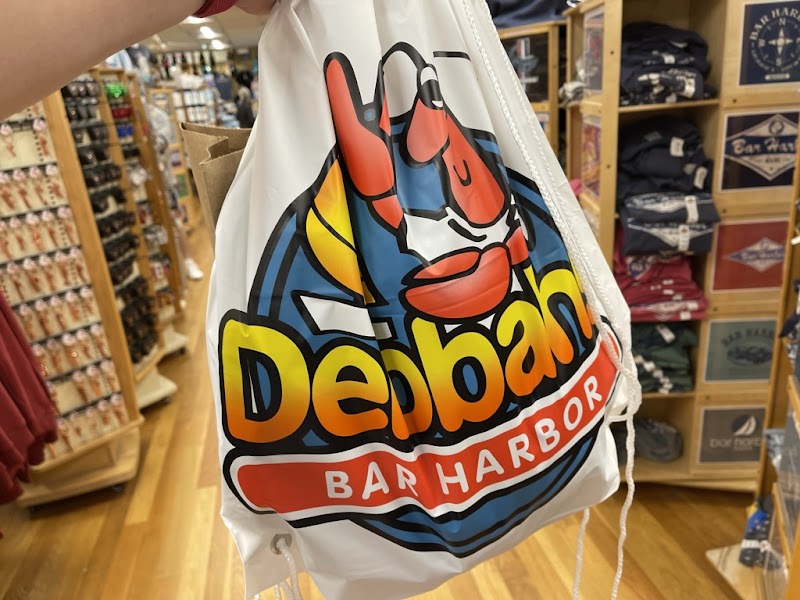 Colorful souvenir drawstring bag with a red lobster graphic and bold yellow lettering, seen in a gift shop at Acadia National Park.