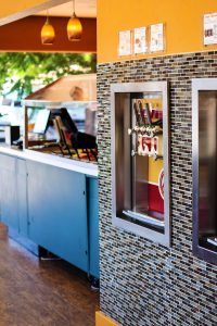 Inside a yogurt shop in Arches National Park with orange walls, mosaic tile, blue counter, and a multi-tap beverage station.