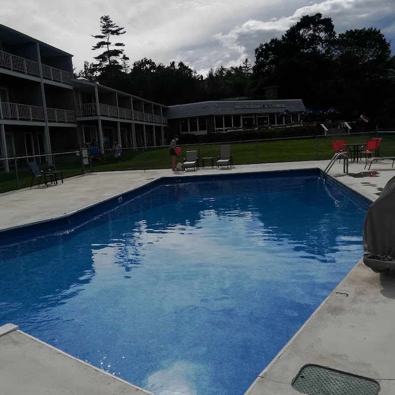 Blue rectangular pool with seating, two-story lodge wings, and restaurant in Acadia National Park.