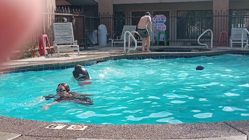 Swimmers in a bright campground pool at Yellowstone National Park, with lounge chairs and a fence around the deck.
