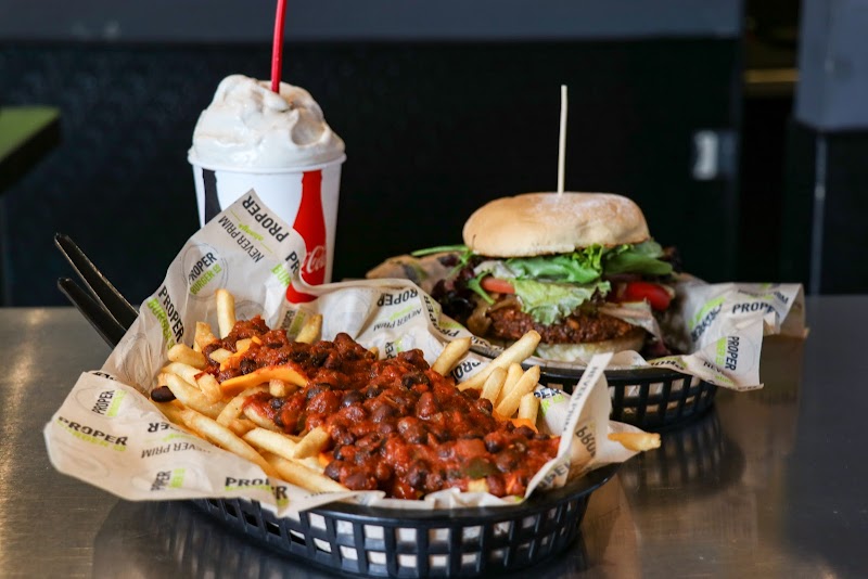 Arches National Park dining scene with a cheeseburger, a basket of chili fries, and a vanilla milkshake on a metal table.