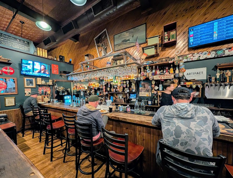 Cozy wooden bar inside Acadia National Park area, patrons sit on stools as bartenders pour drinks.