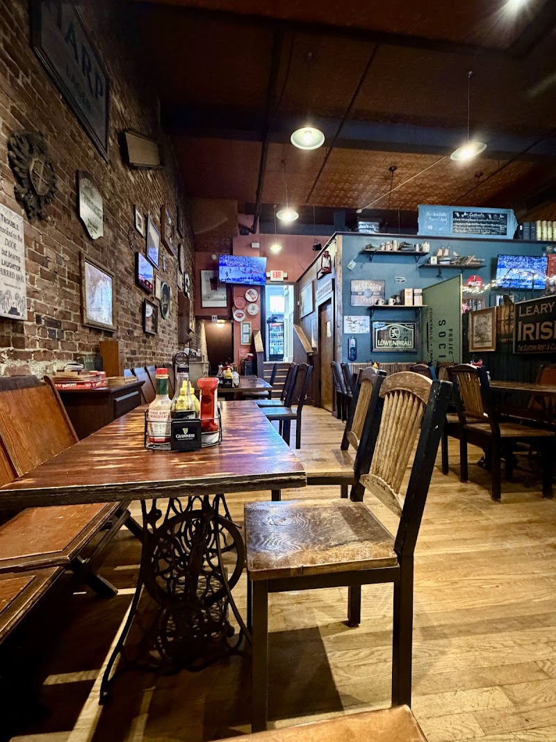 Cozy pub interior with wooden tables and benches, brick walls, vintage signs, and hanging lights in Acadia National Park.