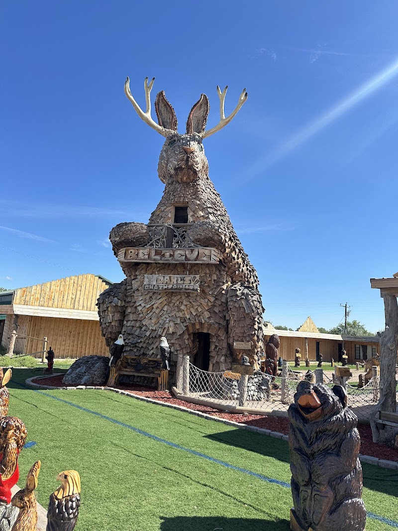 Rustic deer-shaped restaurant building covered in wooden shingles with large antlers and carved figures in Badlands National Park.