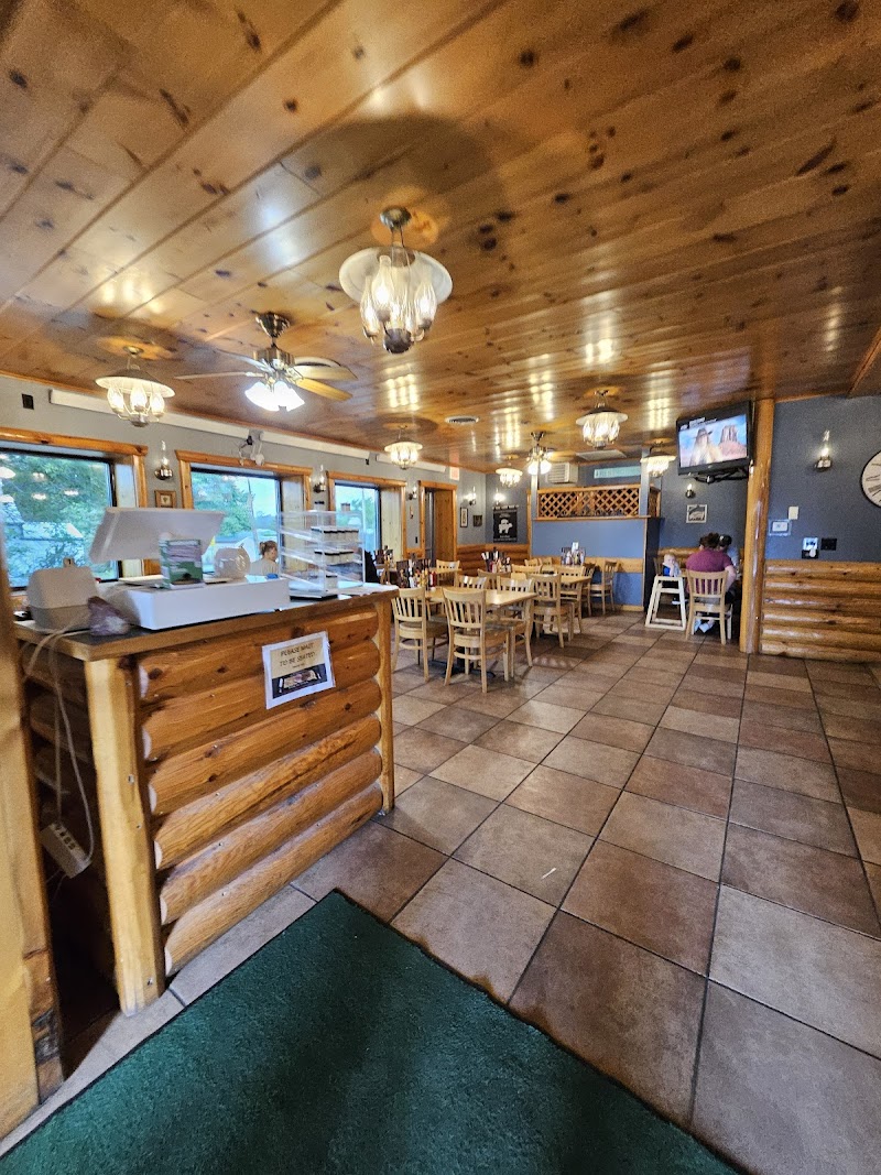Cozy log-cabin restaurant interior with wooden ceiling, chandeliers, front counter, and rows of tables in Badlands National Park.