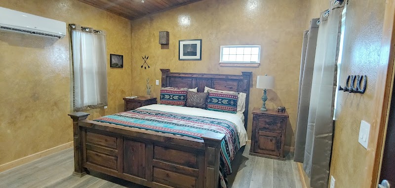 Cozy rustic bedroom in an inn room at Big Bend National Park, featuring dark wood furnishings and patterned textiles.