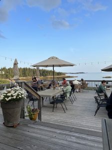 Goose Cove dining deck at Acadia National Park with ocean view, string lights, and outdoor tables.