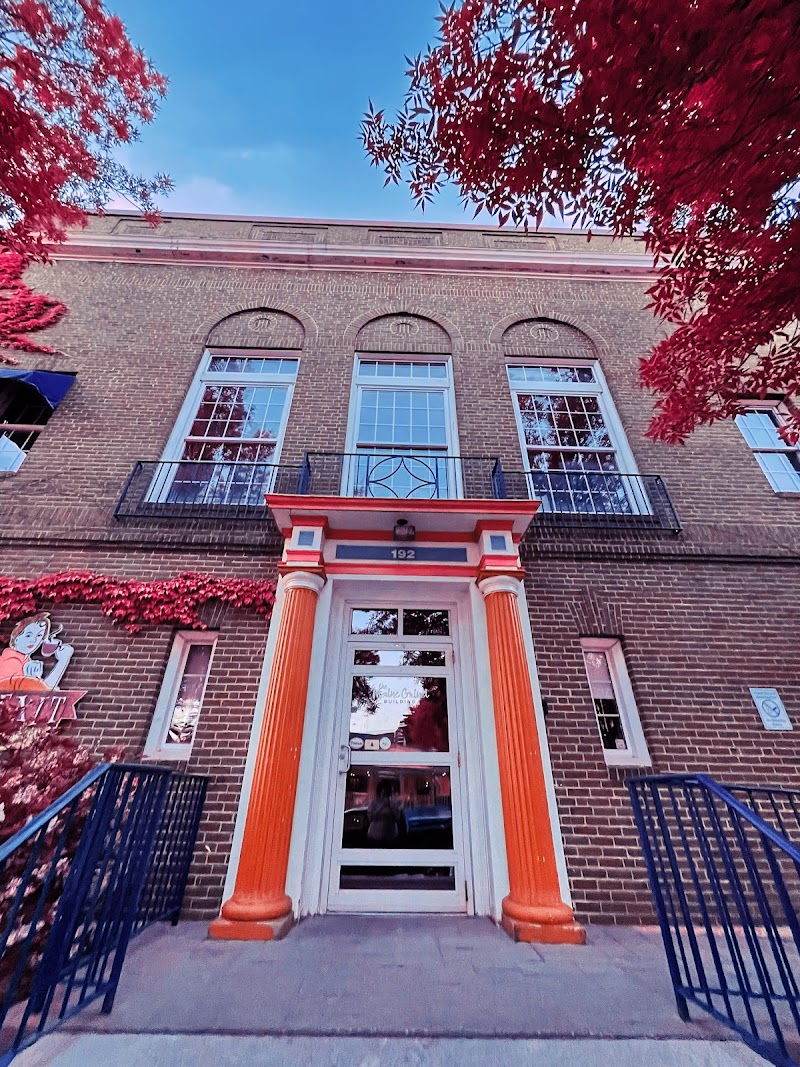 Facade of a brick cafe building with bright orange columns and autumn red foliage at Acadia National Park.