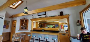 Interior of a dairy bar in Acadia National Park, with a wooden counter, mid-century stools, and warm lighting.