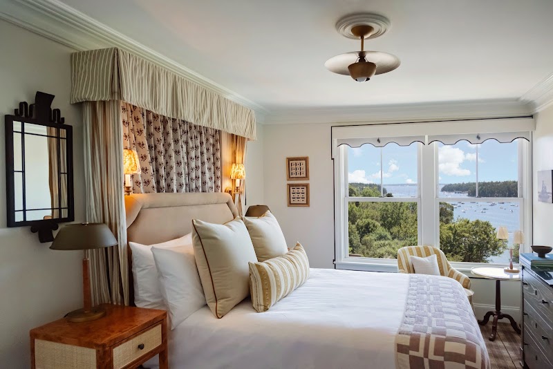 Harbor-view guest room in Acadia National Park, featuring elegant bedding and an ocean-facing window.