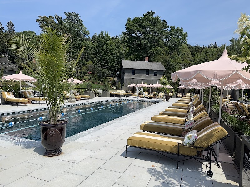 Poolside at a resort in Acadia National Park, with lounge chairs, pink umbrellas, and tropical plants.