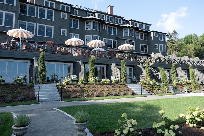 Lodging building with multiple decks and striped umbrellas overlooking a manicured terrace in Acadia National Park.