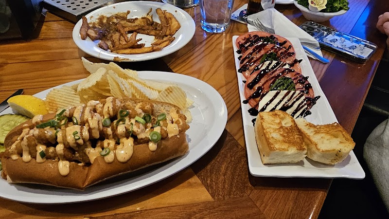 Lobster-topped hot dog with chips and bread on a plate at a tavern-style eatery in Acadia National Park.