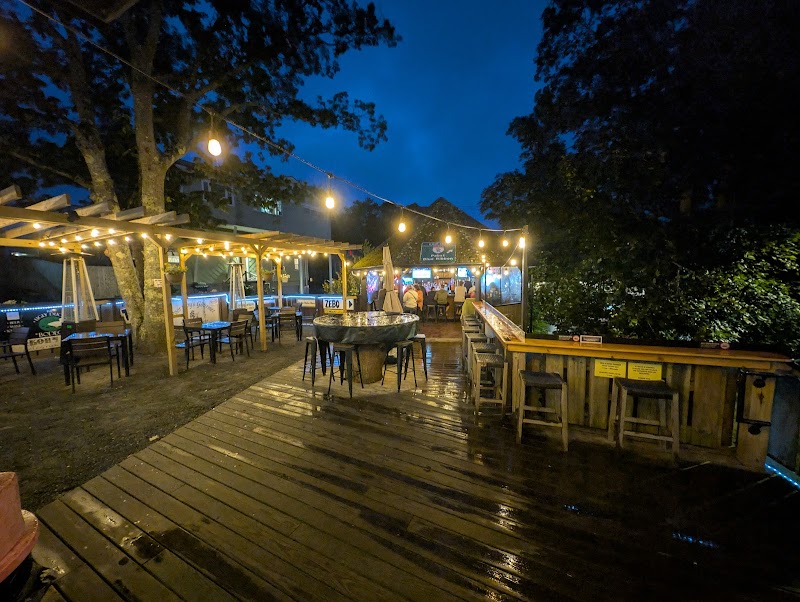 Outdoor dining deck with string lights and wooden furniture, set among trees near Acadia National Park.