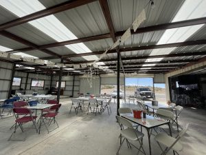 Dining area inside Big Bend National Park featuring a metal-roof shelter, foldable tables, and colorful chairs.